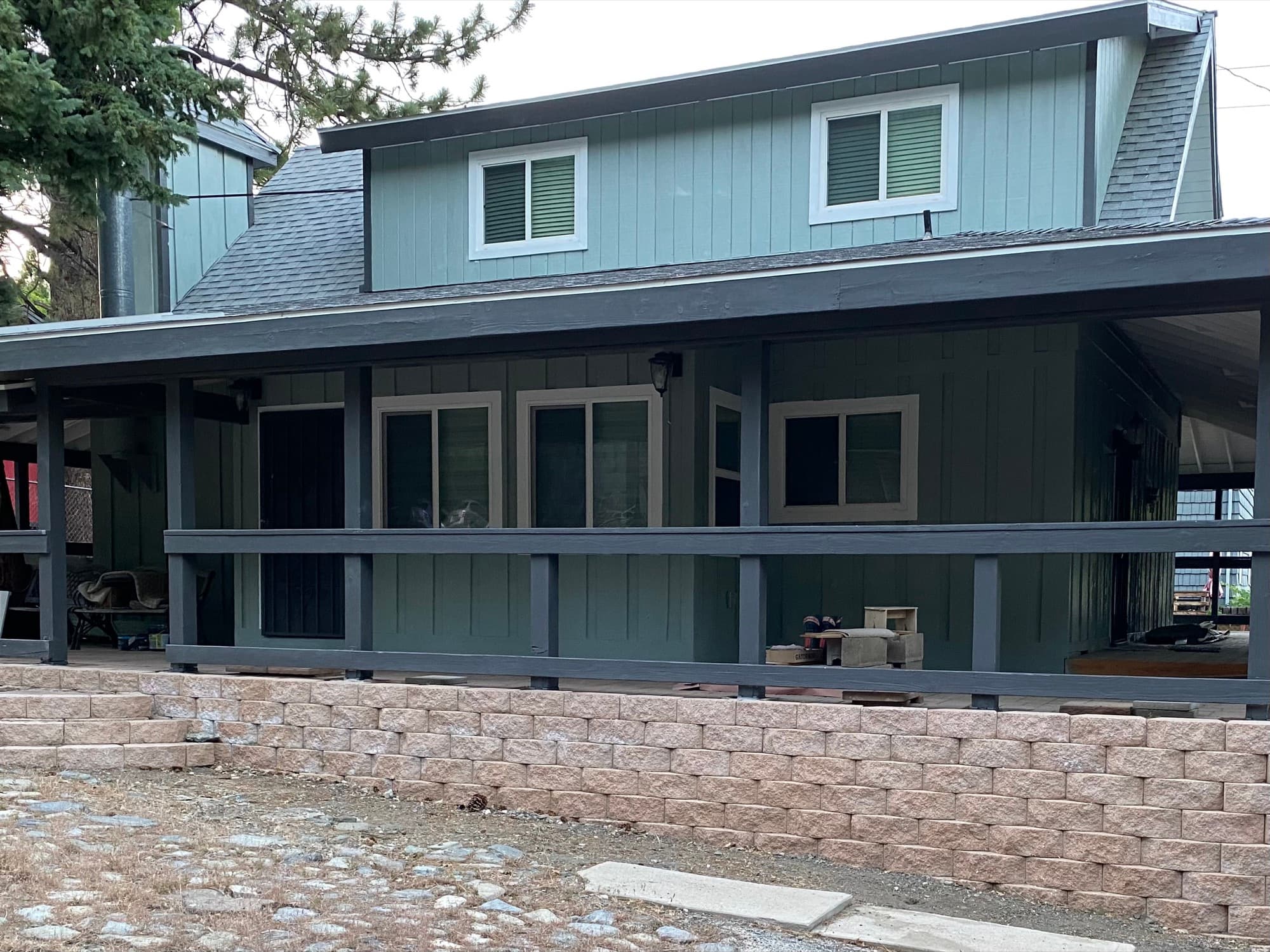 Sage-green board-and-batten residential exterior with charcoal trim and a covered porch.